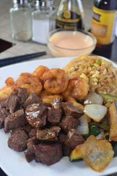 a white plate topped with meat and veggies covered in sauce next to beer bottles