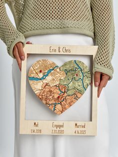 a wooden heart shaped map is held in front of a woman's white skirt