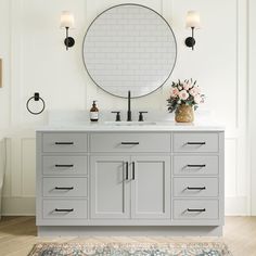 a bathroom vanity with two sinks and a large round mirror above it, along with a rug on the floor