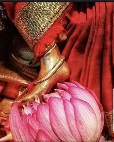 a pink flower sitting on top of a wooden table next to a red cloth covered wall