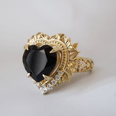 a gold ring with a black heart surrounded by diamonds