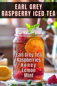 a jar filled with raspberry iced tea next to sliced lemons and mint