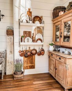 an old fashioned kitchen with wooden cabinets and dishes hanging on the wall in front of it