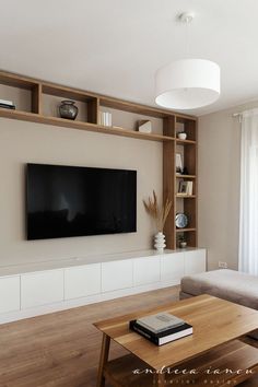 a living room with a couch, coffee table and television mounted on the wall above it