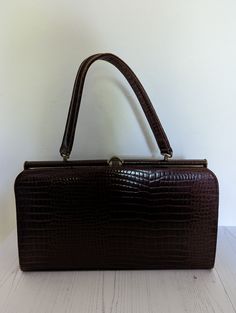 A lovely vintage handbag from the collectible MacLaren of Norwich, England. Made from genuine leather, this bag has a carry handle and is in a traditional boxy shape The handbag is made from brown leather in a snakeskin style. There in one large internal compartments with a smaller zip pocket on the inside and a pouch on the opposite side. The handbag fastens with a top clasp which is still very strong The handbag measures approx 33cm x 19cm x 7cm. The strap is 34cm long. There are some marks to the bag as the photos show but generally it is in very good vintage condition handbag and dates from the 1960s Ideal bag to complete a vintage outfit Vintage Brown Shoulder Bag With Hasp Closure, Vintage Square Box Bag, Classic Evening Satchel In Rectangular Case, Classic Evening Satchel In Rectangular Shape, Classic Evening Satchel With Rectangular Case, Vintage Shoulder Box Bag For Daily Use, Retro Satchel Box Bag With Top Carry Handle, Vintage Rectangular Bags For Vintage Events, Vintage Brown Bag With Hasp Closure