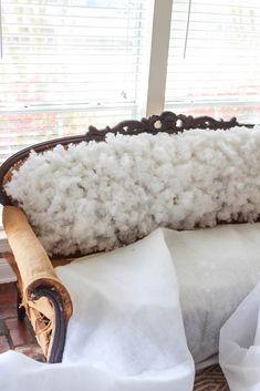 a bed with white sheets and pillows in front of a window