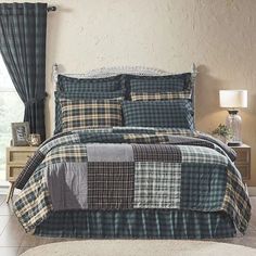 a bed in a room with a plaid comforter and pillows on top of it