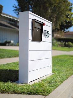 a white mailbox sitting on the side of a road next to a green field