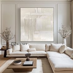 a living room filled with white furniture and art work on the wall above it's coffee table