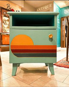 an antique dresser painted in shades of blue, orange and yellow with the sun on it