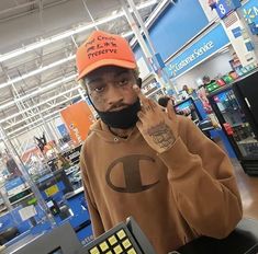 a man with a beard and orange hat is holding a cash register in a store