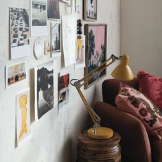 a living room with pictures on the wall and a lamp next to it, in front of a couch