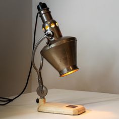 a lamp that is sitting on top of a table next to a light bulb and cord