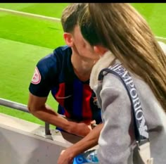 a man and woman kissing each other at a soccer game