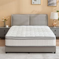 a bed with a white mattress sitting on top of it next to a night stand