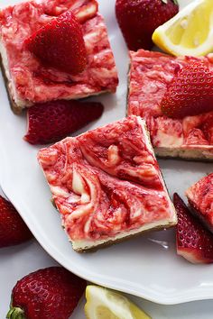 slices of strawberry cheesecake on a plate with lemons and strawberries