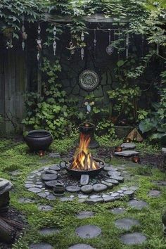 an outdoor fire pit in the middle of a garden with stones and plants around it