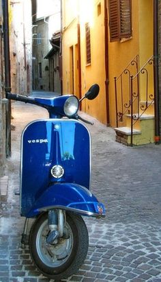 a blue scooter parked on the side of a street in an alleyway