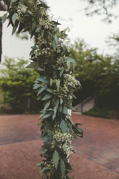 an outdoor wedding ceremony with greenery and white flowers on the side of the aisle