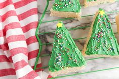 christmas tree cookies on a cooling rack with red and white striped towel next to them