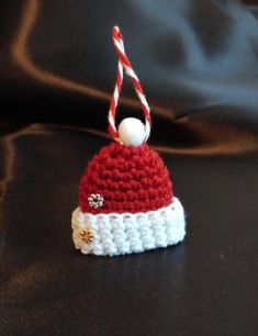 a red and white crocheted hat with a candy cane hanging from it's end