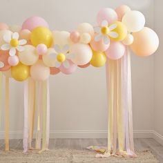 balloons and streamers are arranged on the floor in front of a wall with flowers