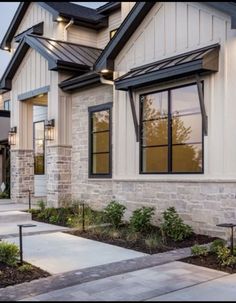 an exterior view of a home with stone and brick sidings, windows, and landscaping