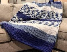 a blue and white crocheted blanket sitting on top of a couch next to a pillow