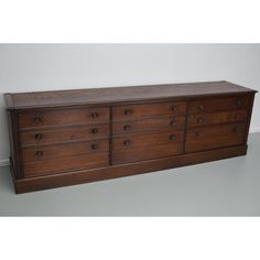 a large wooden dresser sitting on top of a gray floor next to a white wall