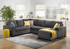 a living room with gray couches and yellow throw pillows on the rug in front of windows