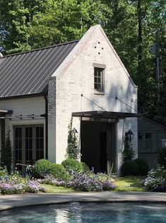 a house with a pool in front of it and lots of flowers around the yard