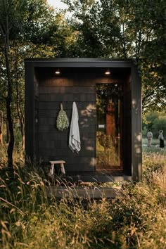 an outhouse in the woods with a towel hanging on it's door and a bench