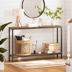 a console table with books, plants and a mirror on the wall in a living room