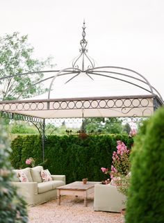 an outdoor living area with couches, tables and a gazebo in the background