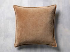 a brown pillow sitting on top of a wooden floor next to a white and gray wall