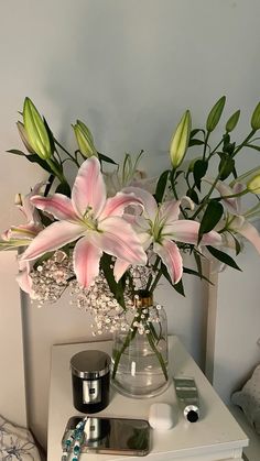 a vase filled with pink flowers sitting on top of a white table next to a night stand