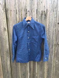 This is a great 70's button up that is stained up and looks amazing. If you want something that is well worn and is super comfortable, get this beauty in your life now. Measurements: Pit to pit: 16 1/2 inches Collar to bottom front: 20 inches Collar to bottom back: 23 inches Sleeve Length (from collar): 25 1/2 inches Shoulder to shoulder: 14 1/2 inches Size on tag: no tag size (measures like women's Small/XS) Vintage Pre-washed Fall Shirt, Vintage Summer Shirt With Button Cuffs, Vintage Blue Shirt For Fall, Vintage Cotton Button-up Shirt, Retro Cotton Shirt With Snap Buttons, Vintage Fitted Pre-washed Tops, Fitted Vintage Pre-washed Tops, Vintage Blue Button-up Shirt, Vintage Blue Shirt With Snap Buttons