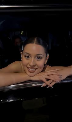 a woman is smiling while sitting in the back of a car