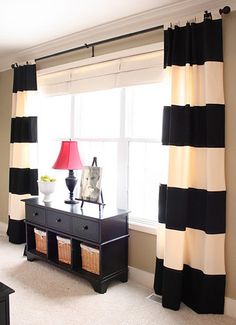 a black and white striped curtain hangs in front of a window with two lamps on it