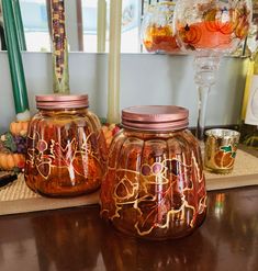 two glass jars sitting on top of a wooden table next to candles and other items