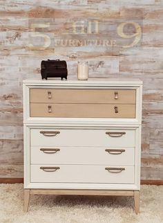 a white dresser sitting on top of a carpeted floor next to a wooden wall