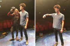 two people standing on a stage in front of a red chair and one person pointing at something