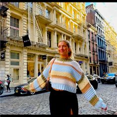 a woman standing in the middle of a street with her hands on her hips and smiling at the camera