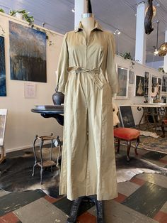 "Vintage 1970s jumpsuit Beige denim like cotton Zips up the front Elastic waist through the sides and back Ties in front Wrist length sleeves with snaps Square side pockets Wide leg Size small / medium Bust 34\" Waist 26-28\" Rise 14\" Length 52\" Inseam 24\" Hem 2 1/2\" can be let down" Beige Cotton Jumpsuits And Rompers For Fall, Khaki Cotton Jumpsuits And Rompers For Fall, Spring Workwear Full-length Jumpsuits And Rompers, Retro Workwear Jumpsuits And Rompers, Retro Style Workwear Overalls And Rompers, Retro Long Sleeve Jumpsuit For Fall, Retro Long Sleeve Jumpsuits And Rompers For Fall, Vintage Long Sleeve Jumpsuits And Rompers For Fall, Full Length Jumpsuits And Rompers For Spring Workwear