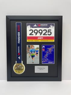 a marathon medal and other items are on display in a black framed shadow box frame