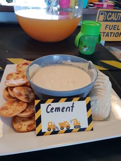 a plate with crackers and dip on it next to a sign that says cement