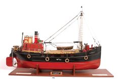 a red and black model boat on display with wooden stand for display ornament