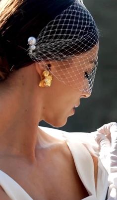 a woman in a white dress wearing a veil and gold earring on her head