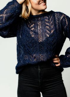 a woman in black pants and a blue sweater is posing with her hands on her head