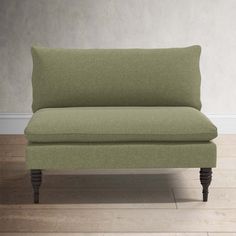 a green couch sitting on top of a hard wood floor next to a white wall